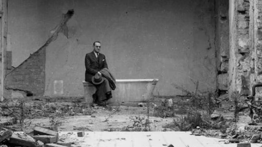 Carl Lutz sitzt auf einer Badewanne in einem vom Krieg gezeichneten Raum.