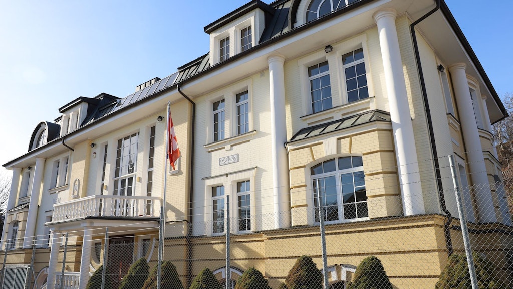 Ein Haus mit hellgelb bemalter Fassade, vor dem eine Schweizer Fahne steht.