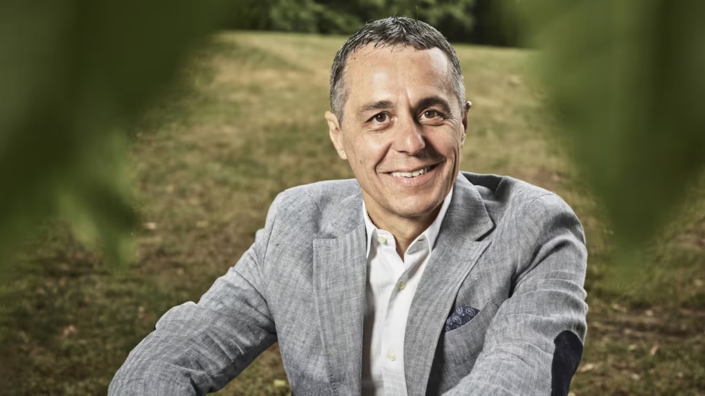 Portrait von Bundesrat Ignazio Cassis, der auf einer Wiese sitzt.