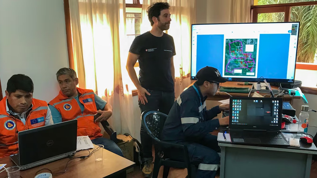 Omar Bellprat steht vor einem grossen Bildschirm in einer Einsatzzentrale, wo reges Treiben herrscht. 