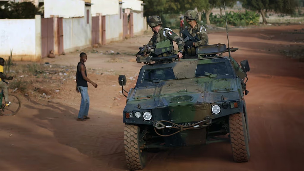 In der Konfliktregion Mali fährt ein Militärfahrzeug mit zwei Soldaten an jungen Männern vorbei.