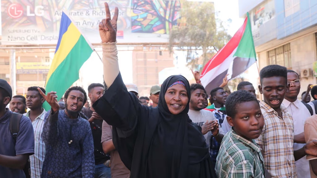 Eine Frau steht in einer Gruppe von Menschen und zeigt das Victory-Zeichen