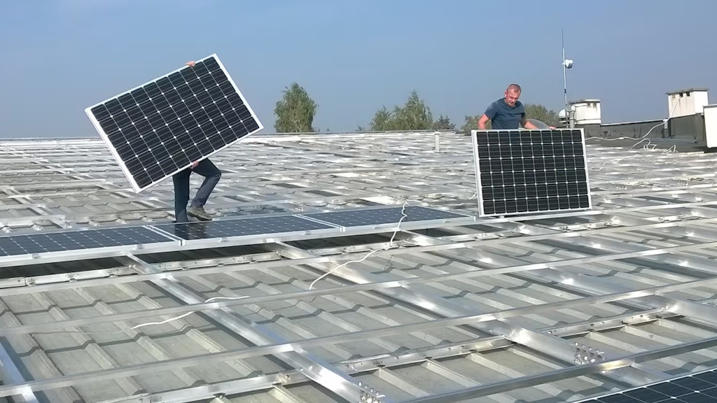 Zwei Techniker installieren Solarpanels auf einem öffentlichen Gebäude.