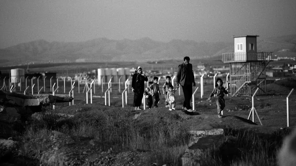 Eine irakische Familie geht durch ein Feld, das mit Streumunition bombardiert wurde.