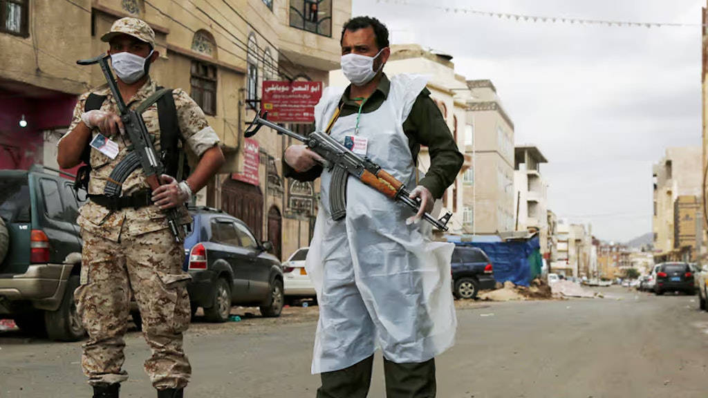 Zwei bewaffnete Soldaten kontrollieren eine Strasse. Beide Soldaten tragen neben einer Schusswaffe Mundschutz, einer trägt Hygienekleidung. 