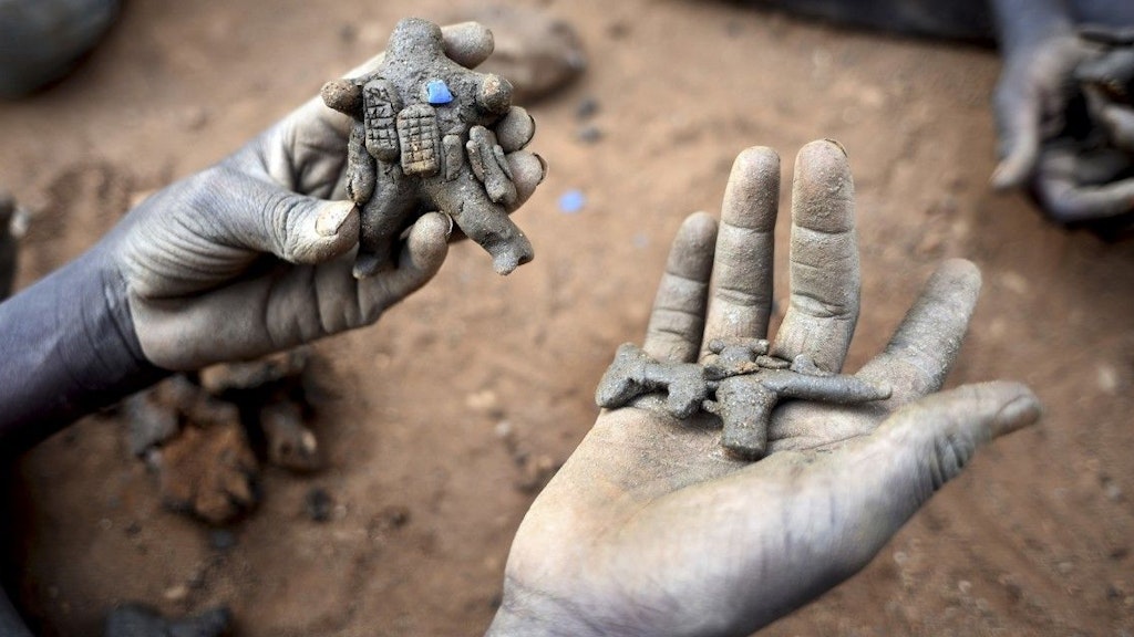 Ein Kind hält einen modellierten UNO-Friedenssoldaten und ein modelliertes Gewehr in den Händen.