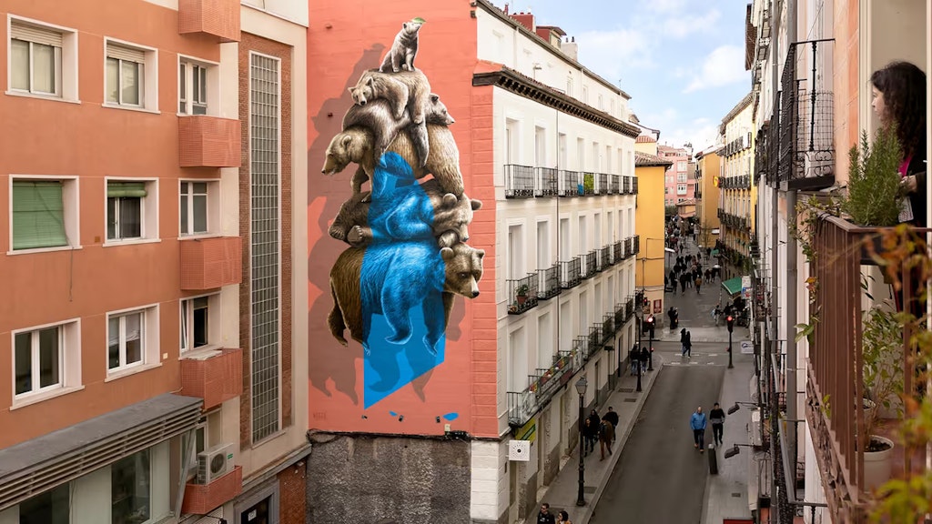 Das Nevercrew-Wandbild  befindet sich in einer Strasse im Zentrum von Madrid. Eine Frau betrachtet das Bild interessiert von ihrem Fenster aus. 