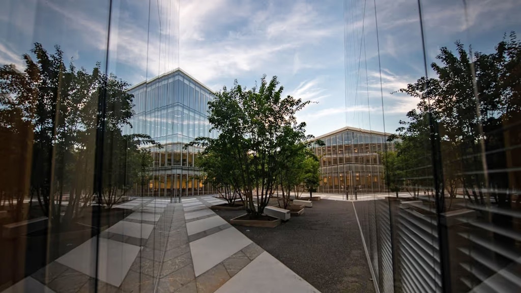 Blick auf zwei Glasfassaden des H-Gebäudes mit einem Baum in der Mitte.