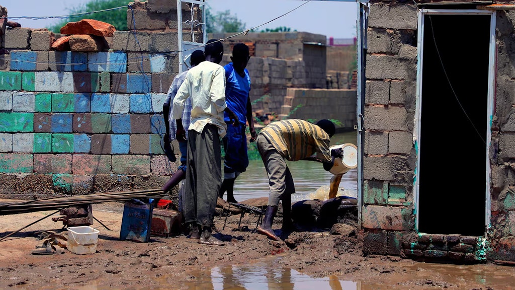 Vier Personen versuchen, ein durch die Wasser- und Schlammflut schwer beschädigtes Haus zu räumen.