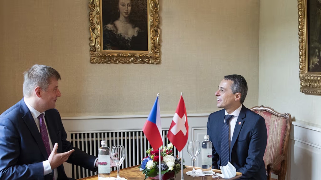 Ignazio Cassis und Tomáš Petříček sitzen an einem Tisch und sprechen.