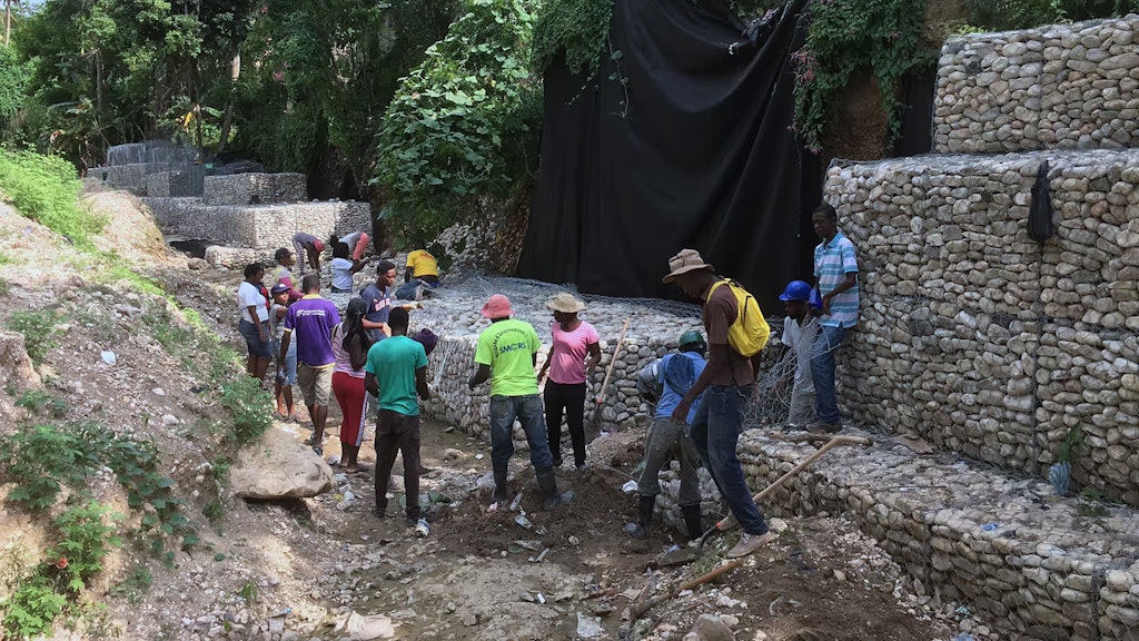 Menschen arbeiten am Bau einer Steinwand, um das Wasser zu kanalisieren.
