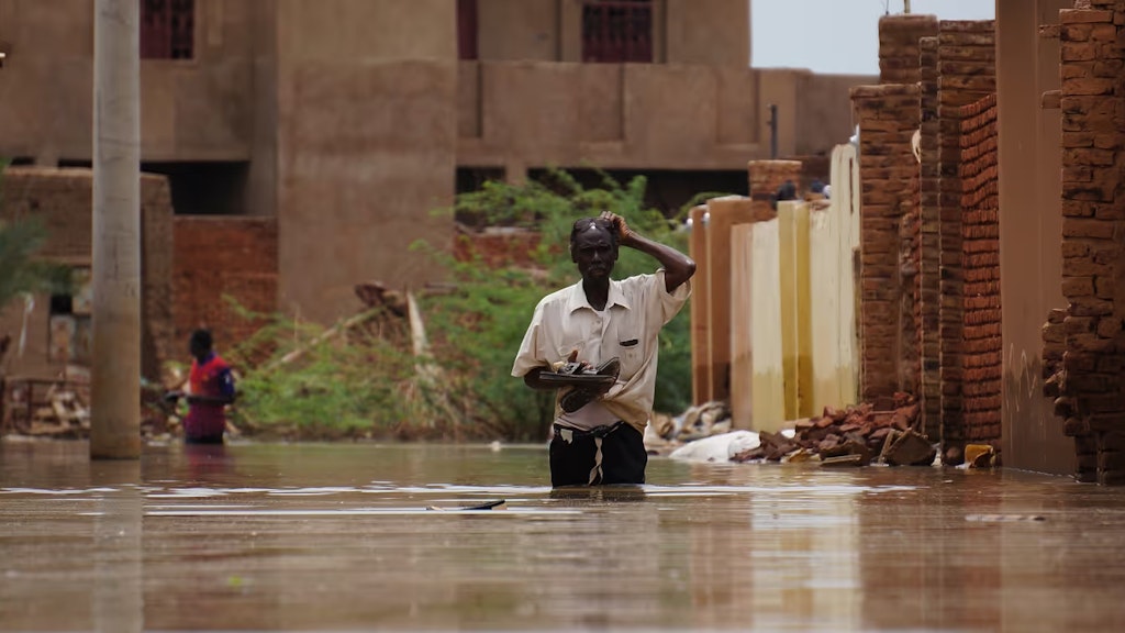 Ein Mann geht eine Strasse hinunter. Seine Beine sind vollständig im Wasser versunken.