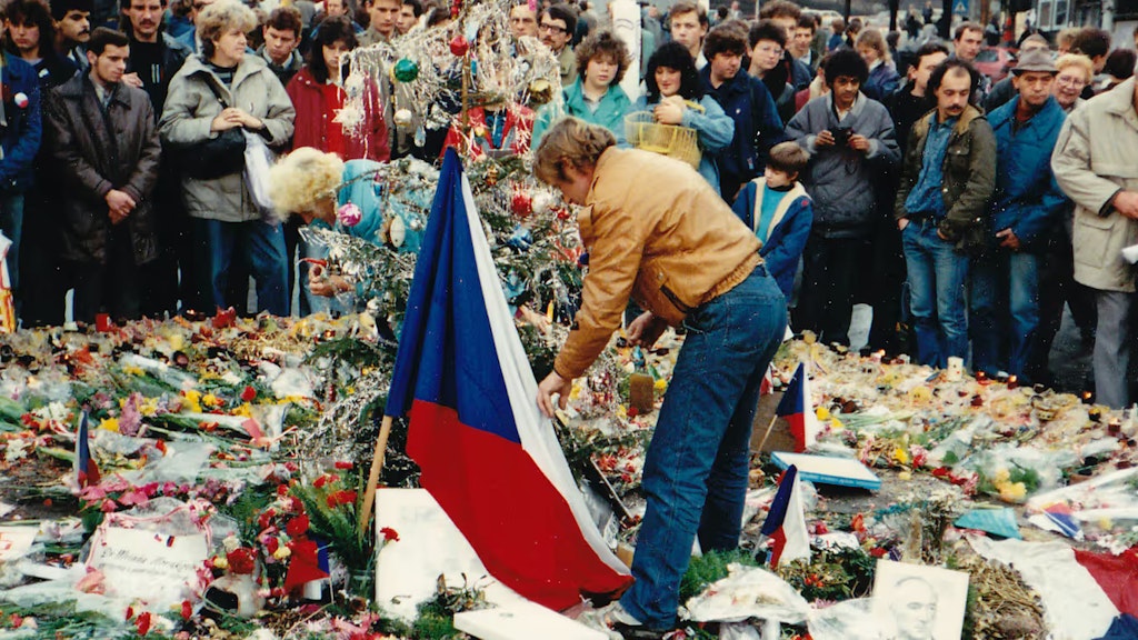 Václav Havel legt umringt von anderen Menschen auf dem Wenzelsplatz Blumen nieder.