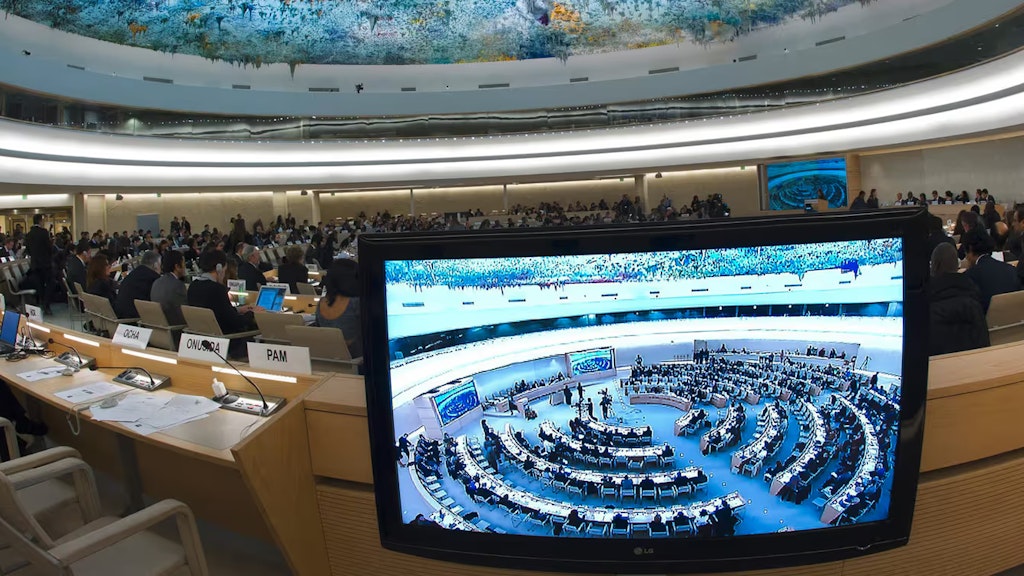Der Saal des UNO-Menschenrechtsrats in Genf. Im Vordergrund ein Bildschirm mit einer Saalaufnahme.
