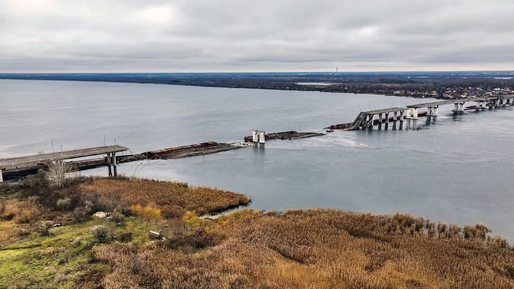 Eine Brücke über einen Fluss, von der Teile der Fahrbahn zerstört im Fluss liegen.