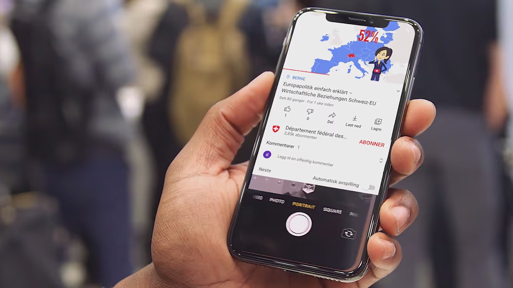 Nahaufnahme einer Hand, die ein Telefon hält. Auf dem Bildschirm ist ein Video mit der Karte der Europäischen Union zu sehen.