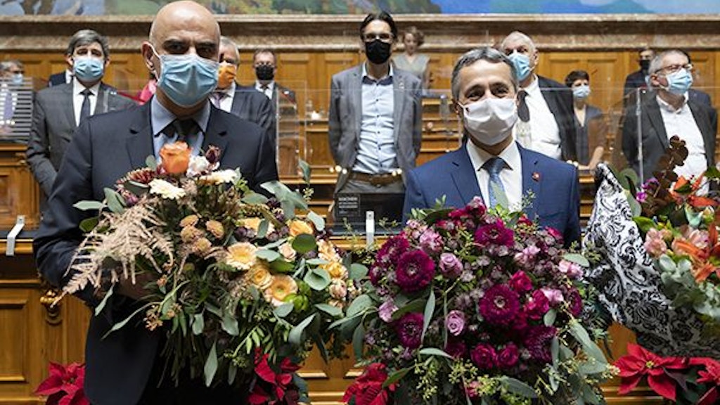 Close-up of Ignazio Cassis and Alain Berset in Parliament during the election. They carry bouquets of flowers.