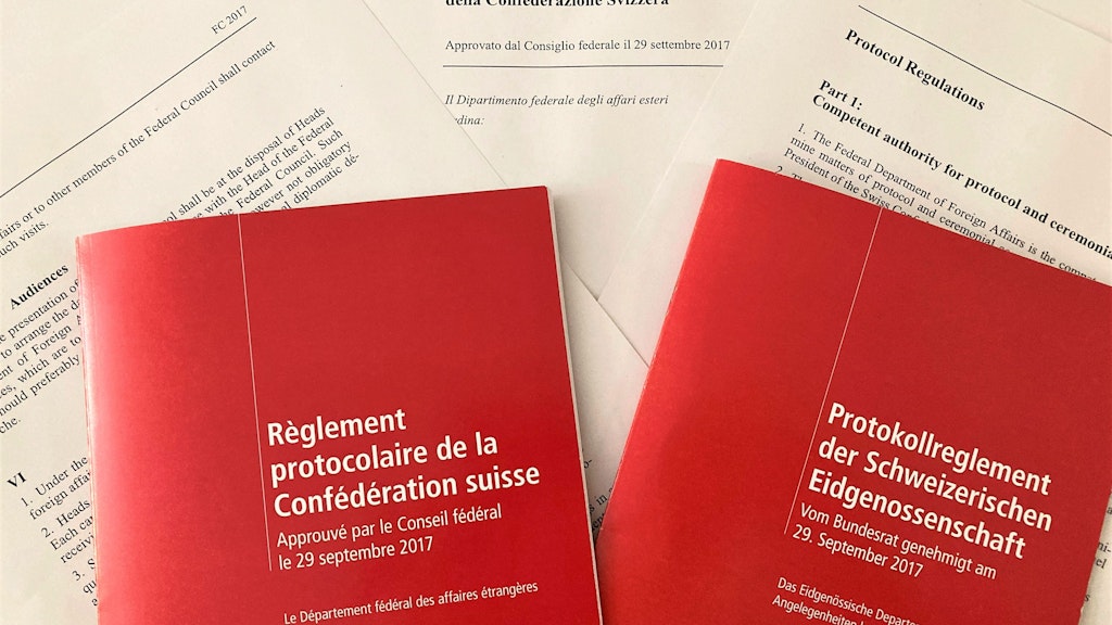 Zwei rote Protokollreglemente liegen auf bedruckten Blättern.