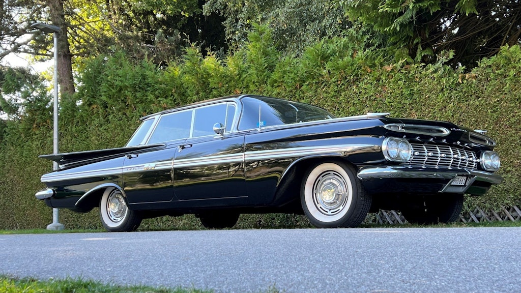 A black, vintage car parked on the side of a road.