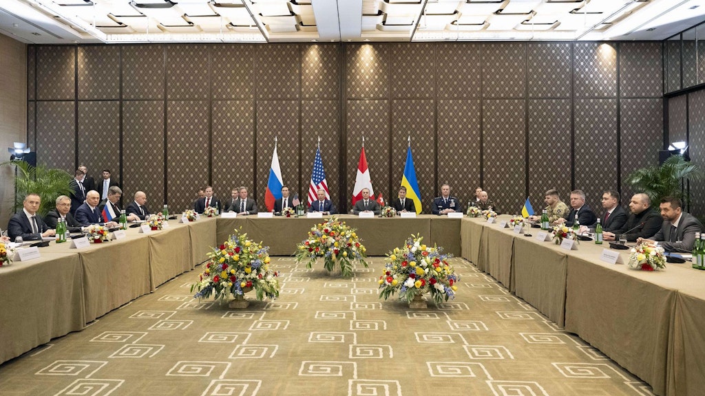 Bundesrat Cassis sitzt am Kopfende der Tische neben der Delegation der USA. Rechts im Bild sitzen die Mitglieder der ukrainischen Delegation, links diejenigen der russischen Delegation.