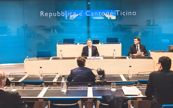 Bundesrat Cassis sitzt den Mitgliedern des Tessiner Staatsrats gegenüber. Rechts von ihm sitzt Staatssekretär Roberto Balzaretti. An der Wand ist «Repubblica e Cantone Ticino» zu lesen.