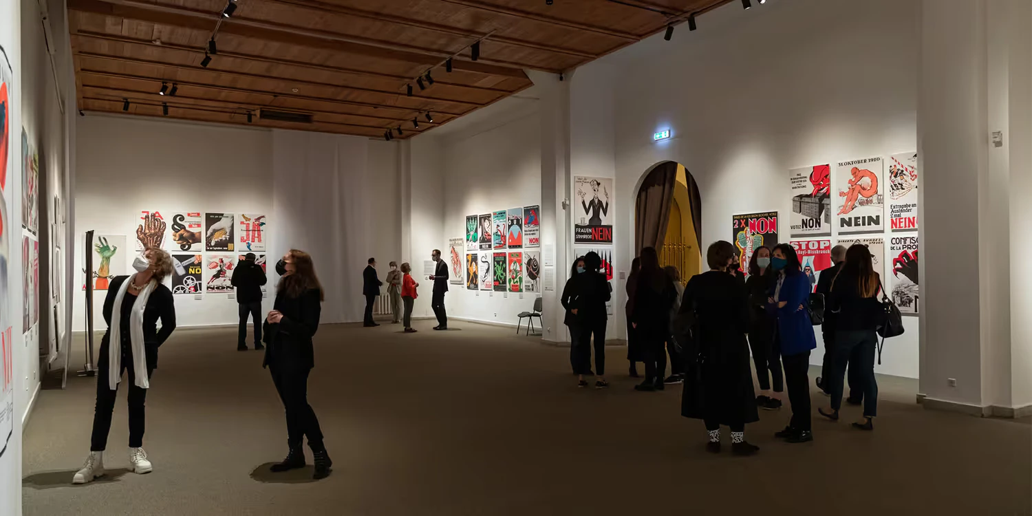In Vilnius betrachten die Besucherinnen und Besucher der Ausstellung Plakate zu schweizerischen Abstimmungsvorlagen der letzten 100 Jahre. 