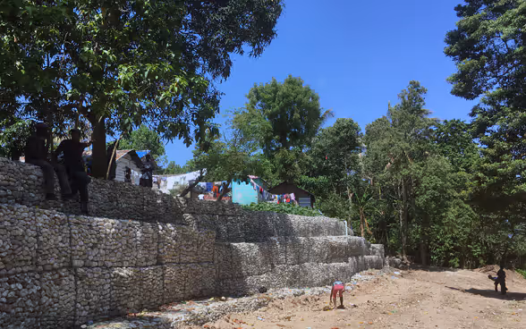 An den Seiten einer unbefestigten Strasse werden Steinbauten errichtet.