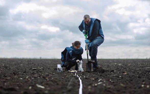 Zwei Fachleute der Schweizerischen Stiftung für Minenräumung bei der Arbeit auf einem Ackerfeld.