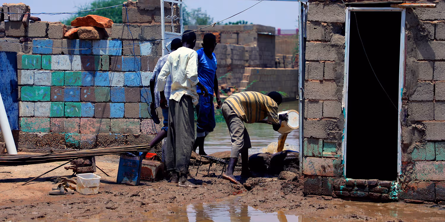 Vier Personen versuchen, ein durch die Wasser- und Schlammflut schwer beschädigtes Haus zu räumen.