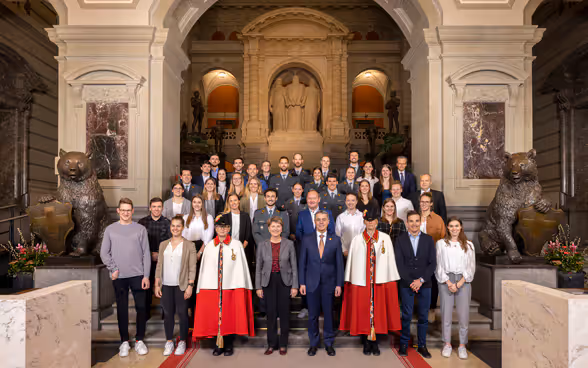 Bundespräsident Ignazio Cassis und Bundesrätin Viola Amherd mit rund 20 Sportlern im Parlamentsgebäude.