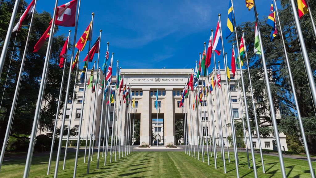Wehende Fahnen stehen in zwei Reihen vor dem Palais des Nations.