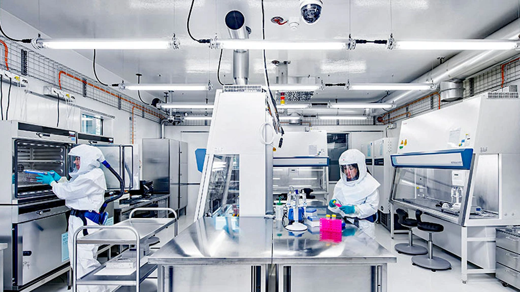 Zwei Personen in Ganzkörperanzügen arbeiten in einem Labor.