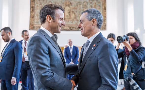 Bundespräsident Cassis und der französische Präsident Emmanuel Macron stehen sich gegenüber und sprechen miteinander.