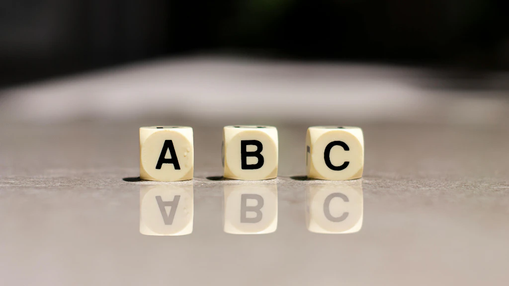 Drei Würfel mit den Buchstaben A, B und C stehen auf einer grauen Oberfläche.
