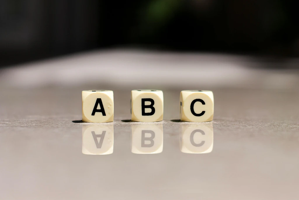 Drei Würfel mit den Buchstaben A, B und C stehen auf einer grauen Oberfläche.