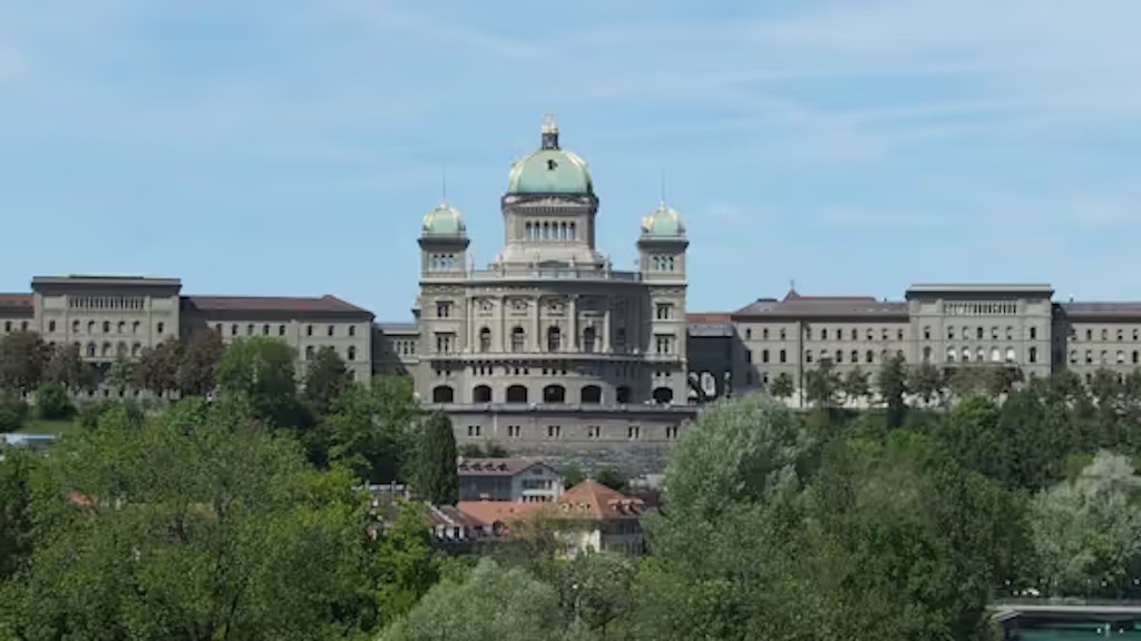 Das Bundeshaus in Bern mit grüner Kuppel, umgeben von Bäumen.