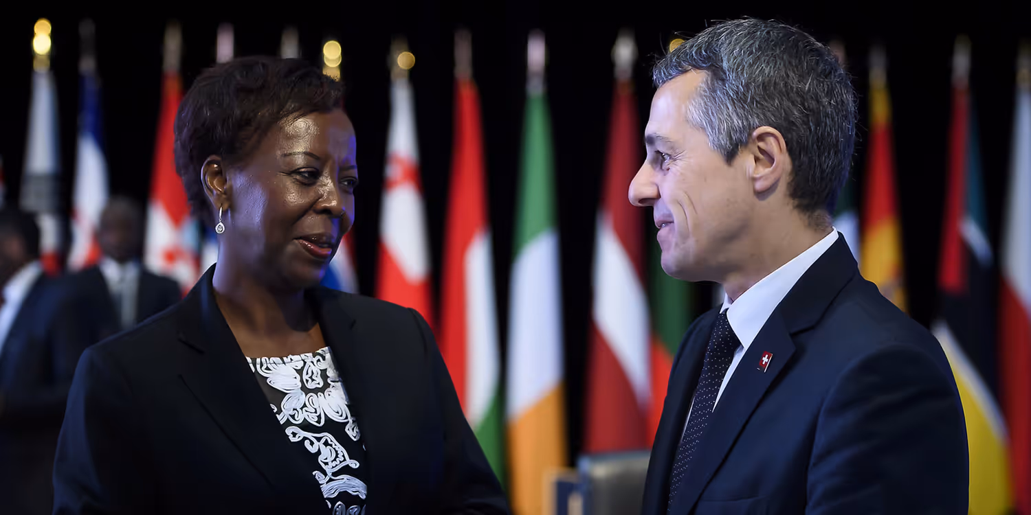 Ignazio Cassis und die Generalsekretärin der Frankophonie, Louise Mushikiwabo, im Gespräch. Im Hintergrund die Flaggen der 54 Mitgliedsstaaten und Regierungen.