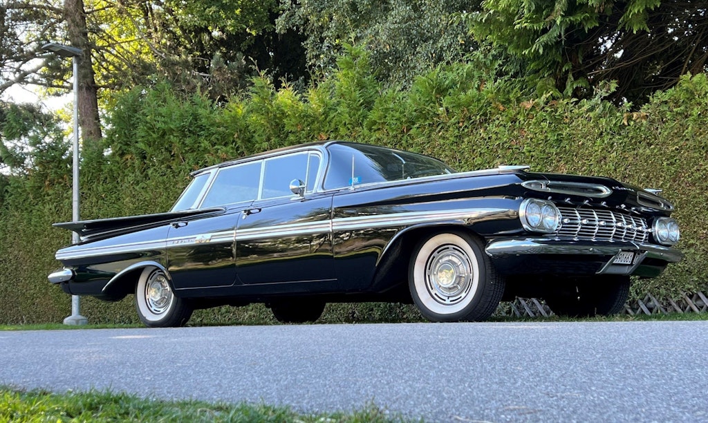 Ein schwarzer Oldtimer ist auf einer Strasse parkiert.