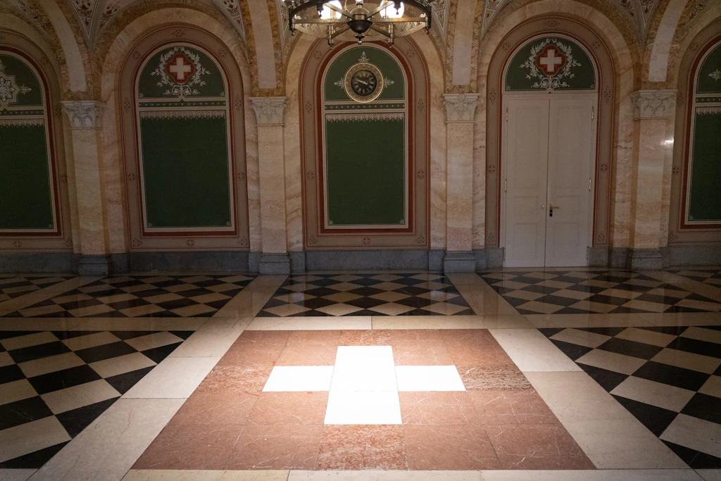 Blick in das Innere vom Bundeshaus West mit einem Schweizer Kreuz auf dem Boden. 