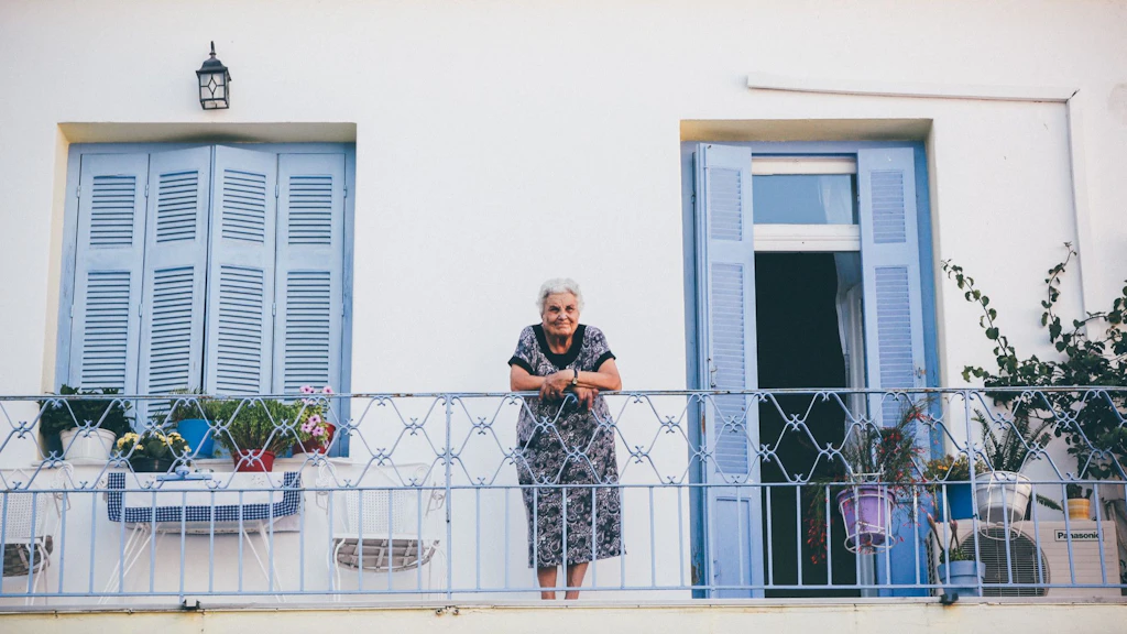 Eine alte Frau steht auf ihrem Balkon.