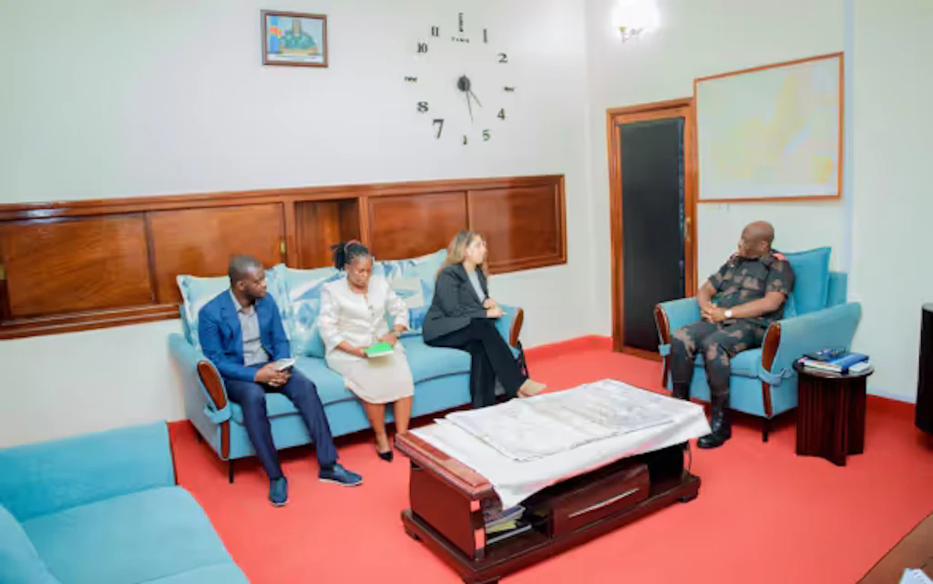 Laura Reymond-Joubin sitzt mit zwei anderen Personen auf einem Sofa. Sie diskutiert mit dem Militärgouverneur der Provinz Ituri, der zu ihrer Linken auf einem Sessel sitzt.