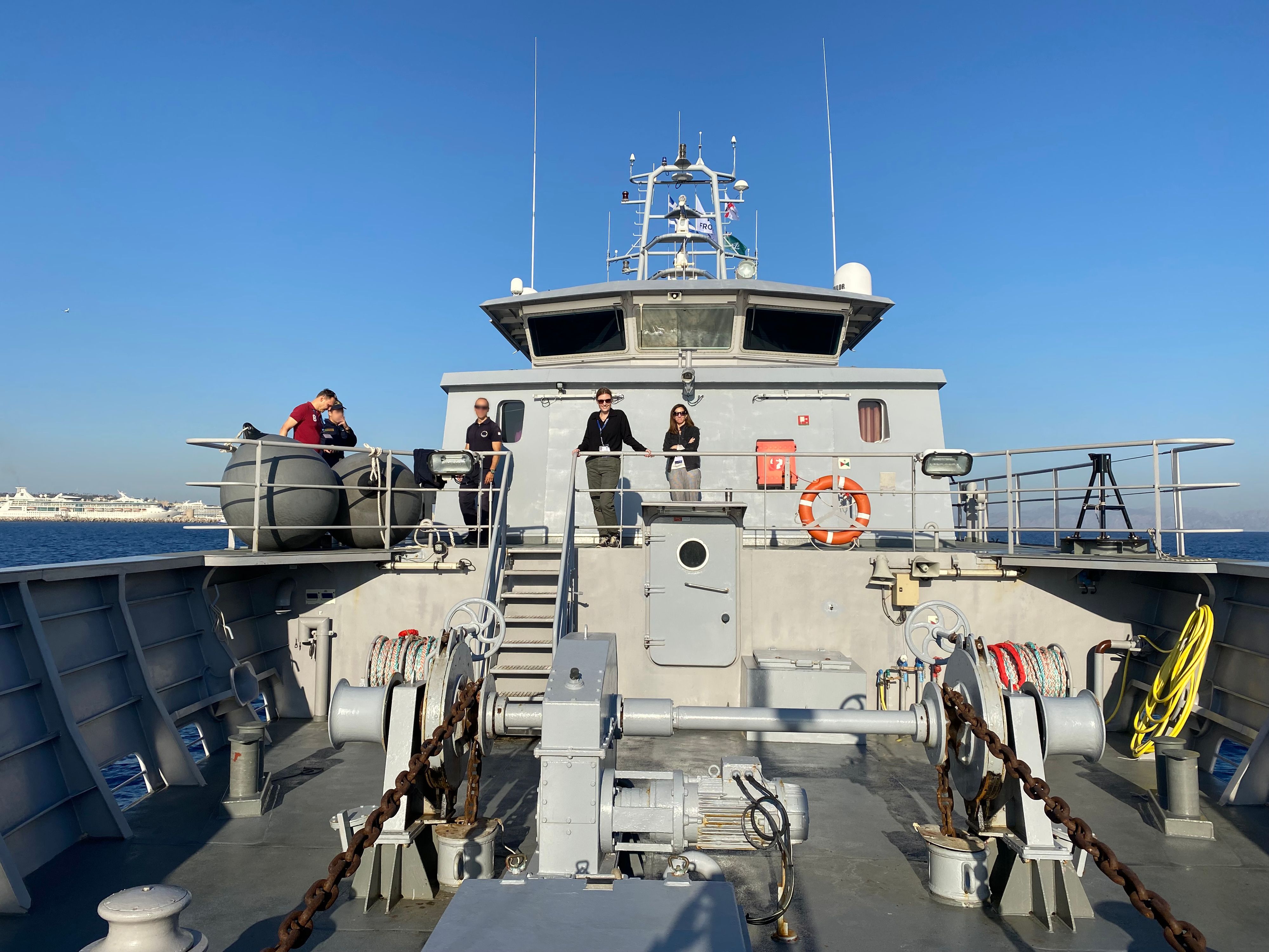 Fünf Personen auf dem Deck eines Schiffes auf dem Meer.