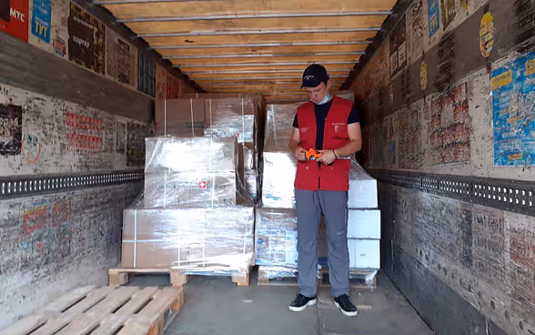 Ein Mann steht im Innern eines Lastwagens vor Paletten mit humanitären Hilfsgüter. 