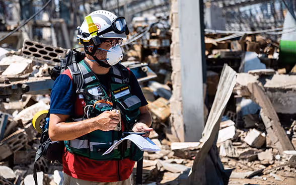 A Swiss Humanitarian Aid expert is standing in the middle of the debris at the port of Beirut.