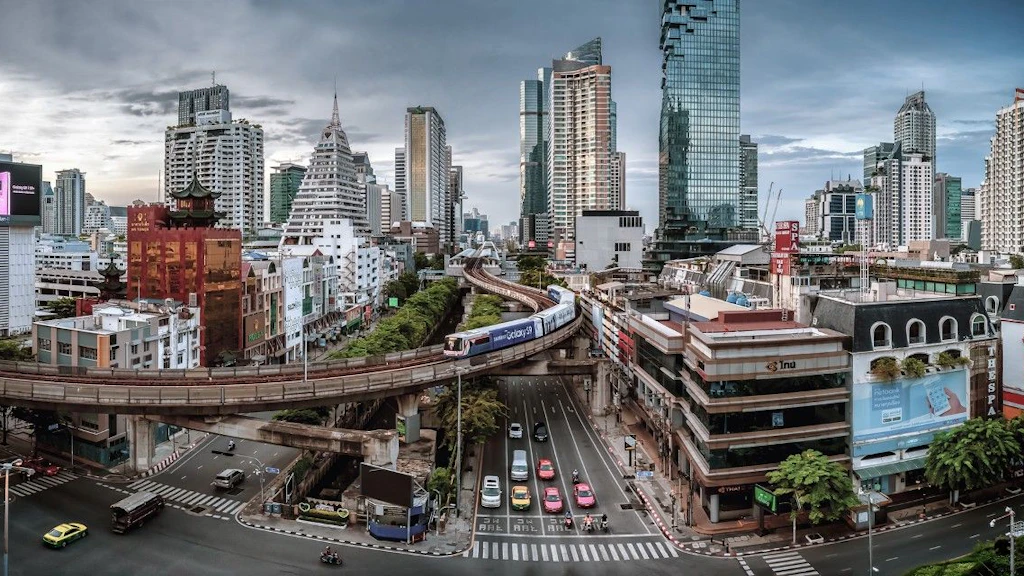 A train travels over a road with buildings in the background.