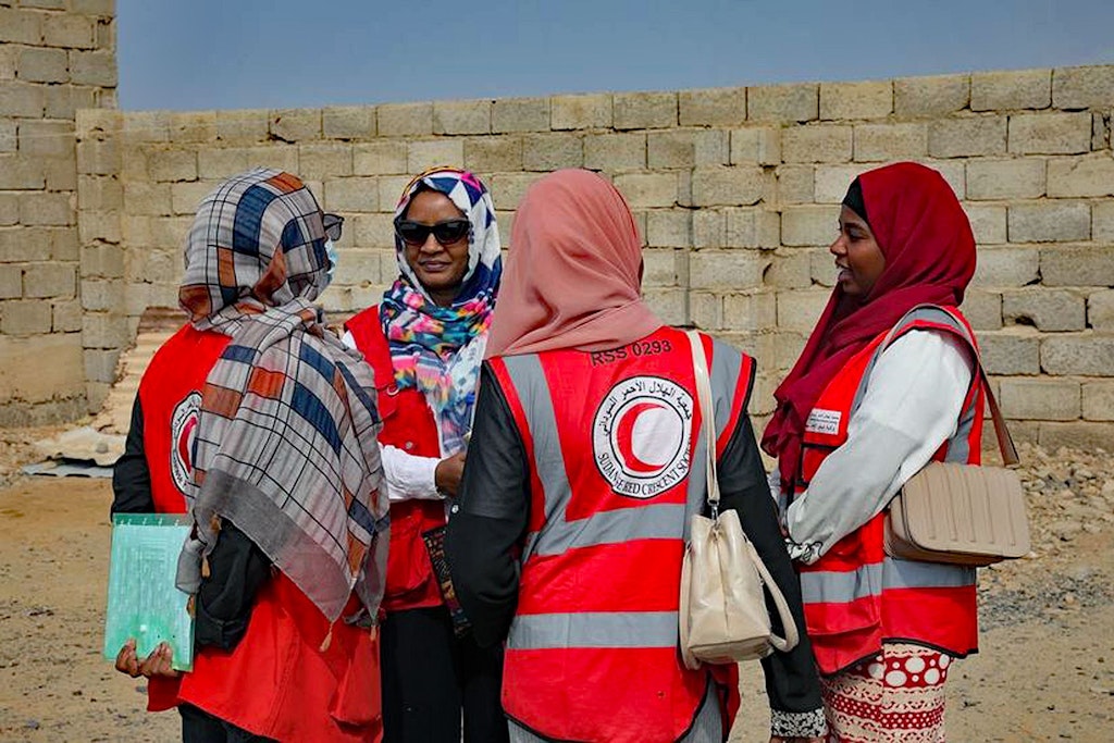The photo shows volunteers from the Sudanese Red Crescent talking to each other in a camp for displaced persons near Port Sudan.