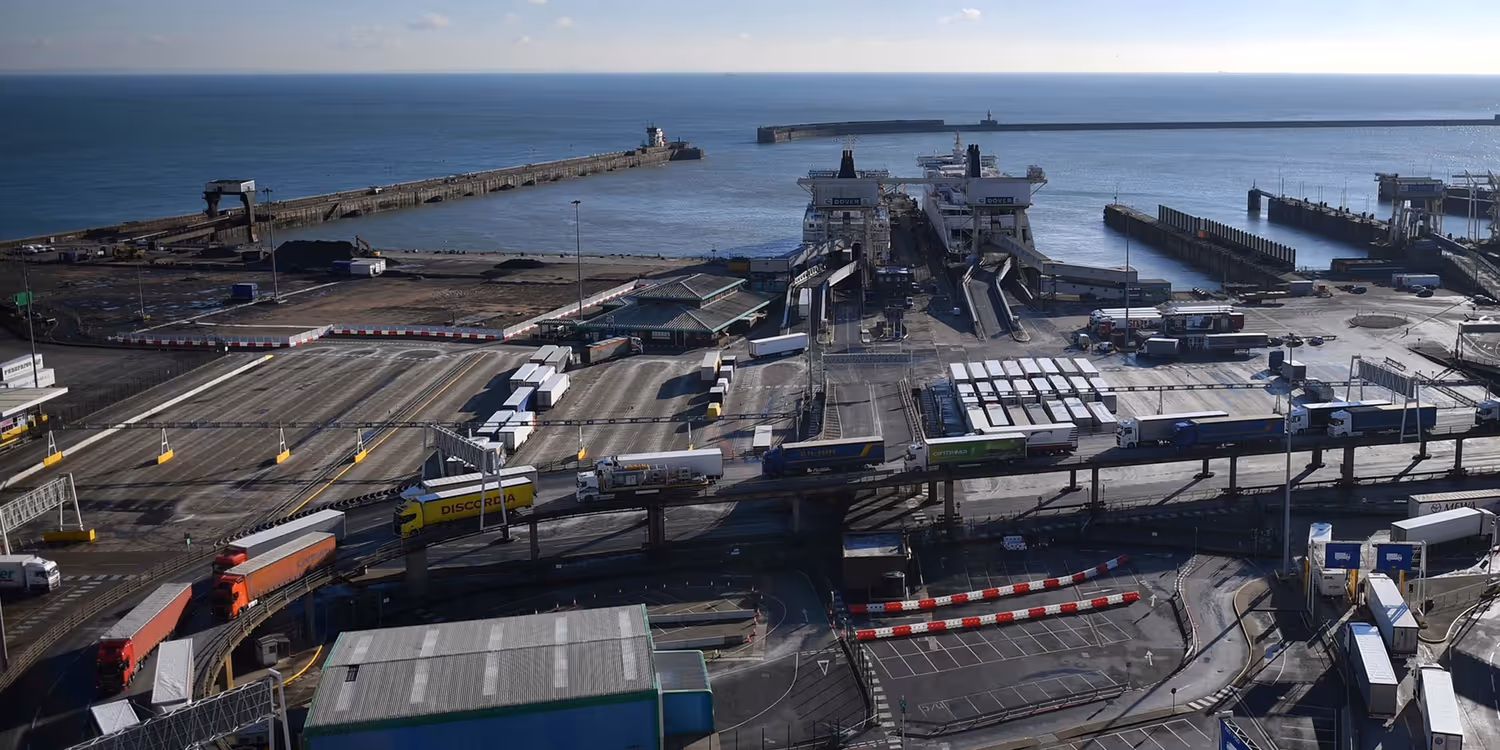 Lorries driving in a row of two on a ramp leading off the ferry into the harbour area.