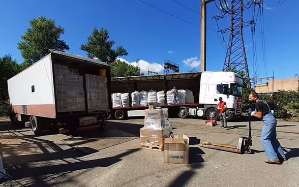Swiss humanitarian aid logisticians load relief supplies into a truck.