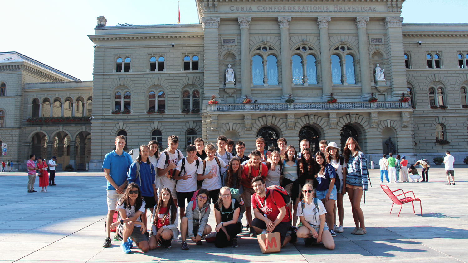 Group photo featuring young attendees in the Bundesplatz in Bern, with the Federal Palace in the background.
