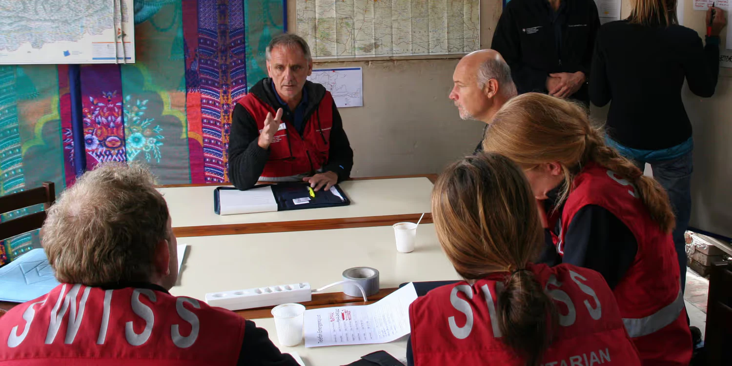 Ueli Salzmann is briefing his team on an upcoming deployment in a makeshift barrack.